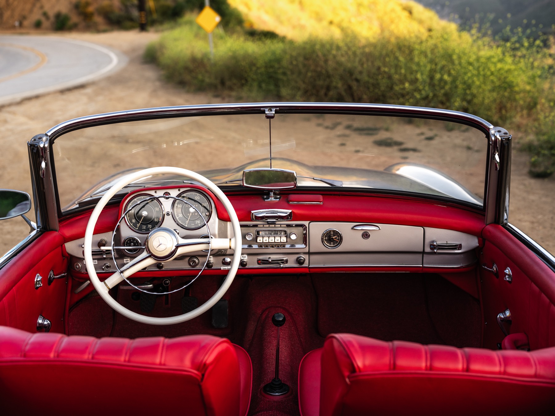 Oxblood red leather cockpit of the 1959 Mercedes 190 SL overlooking a Malibu canyon road