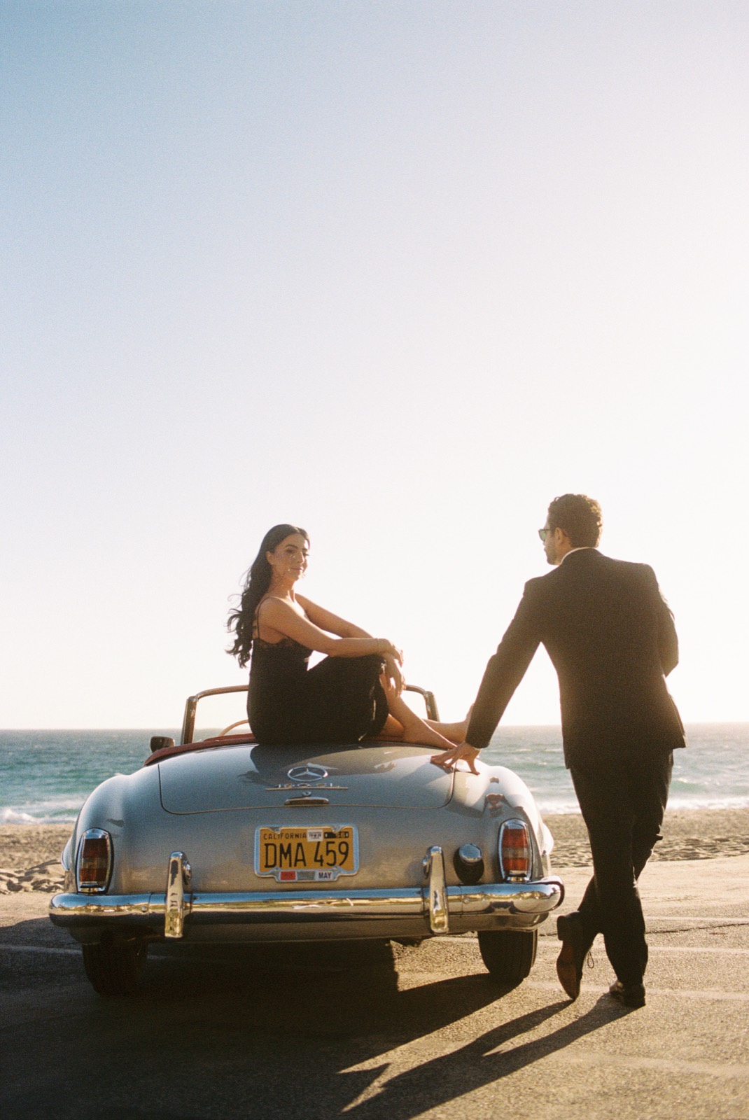 Film photograph of a couple with the silver 190 SL by the Pacific Ocean