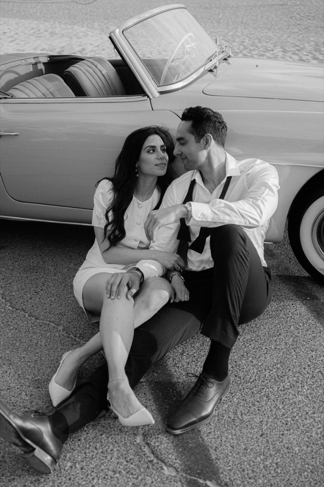 Black and white editorial portrait of a couple seated against the 190 SL