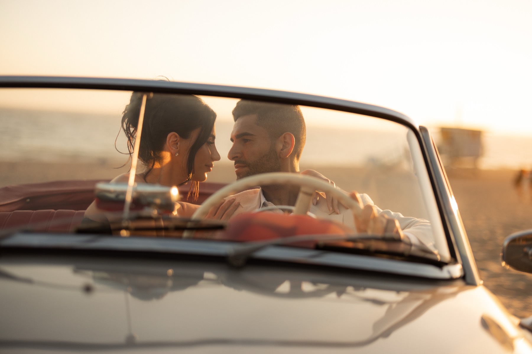 Couple photographed through the windshield of the 190 SL at a Malibu beach at golden hour